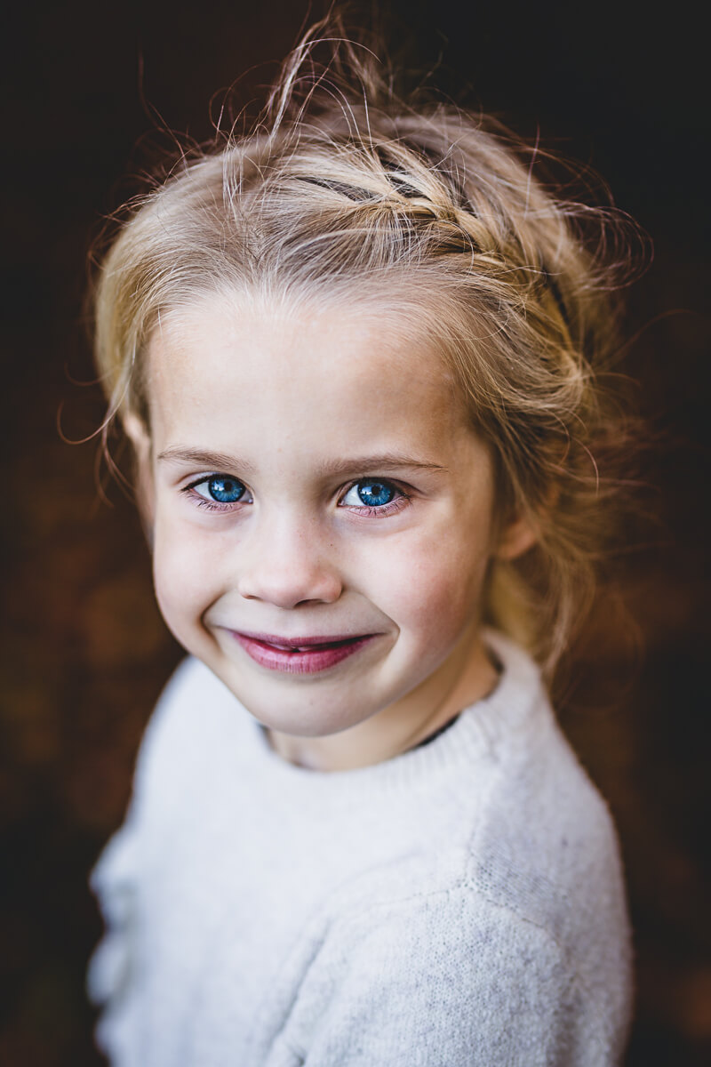 Little girl with blue eyes smiling during family portrait shoot in Dorset
