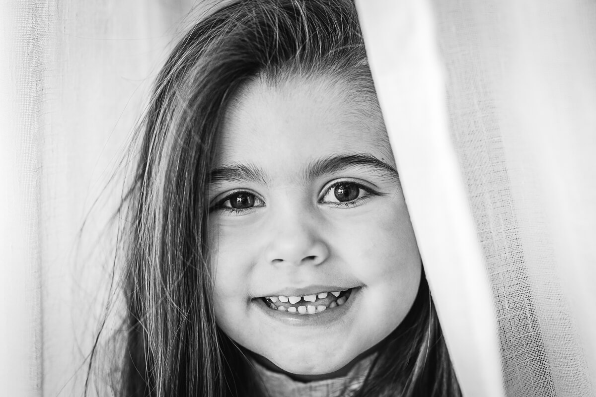 Black & White image of little girl in chiffon curtain