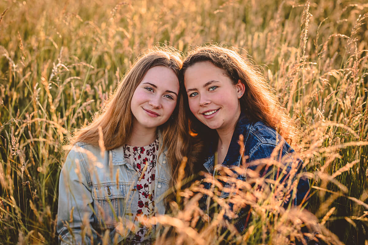 Portrait of two sisters in a field during golden hour by Dorset Family Photographer