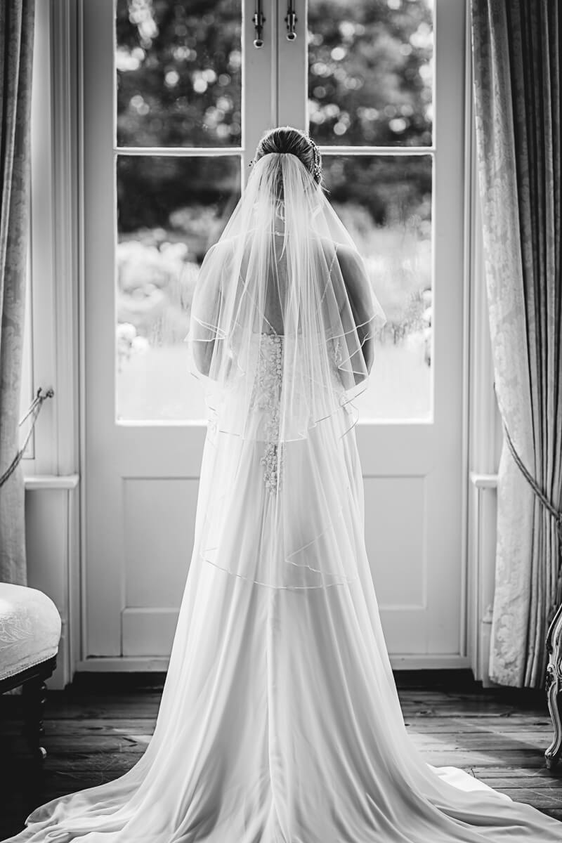 Back of the brides dress as she looks out of a window at Parley Manor, Dorset