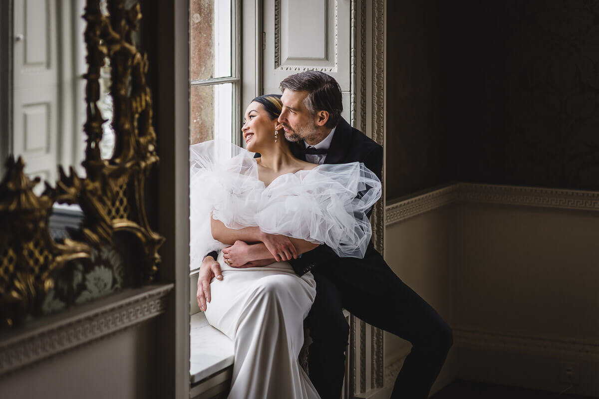 Bride and Groom sitting on a window seat looking out the window at St Giles House