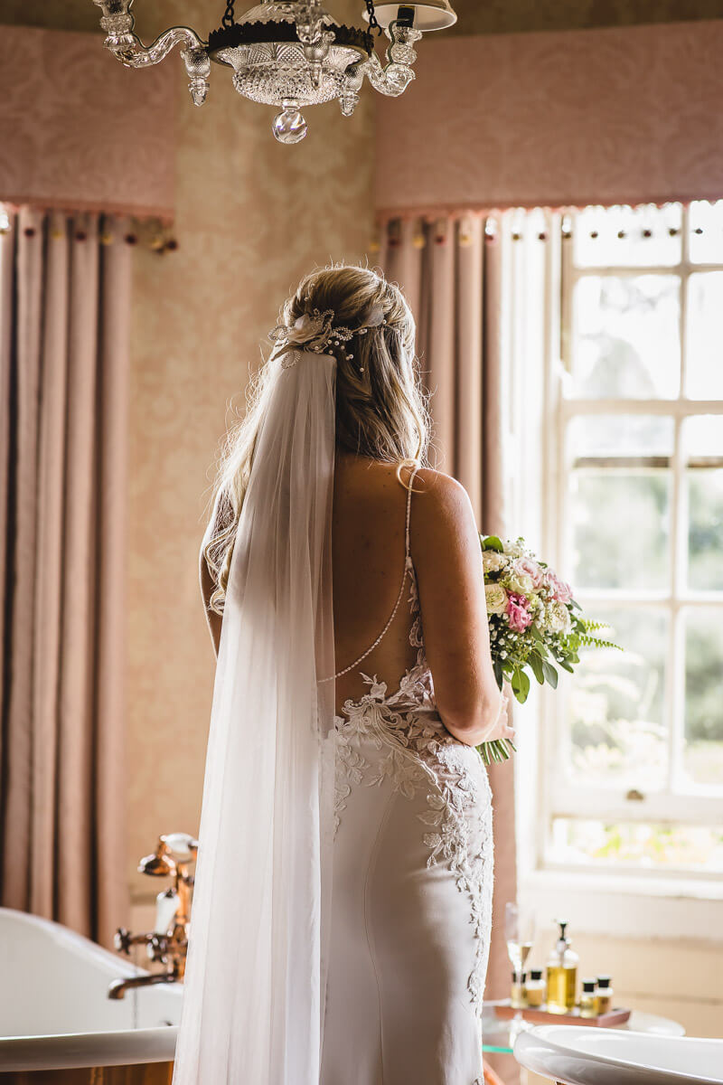 Bride looking out window before the the ceremony at Pylewell Park