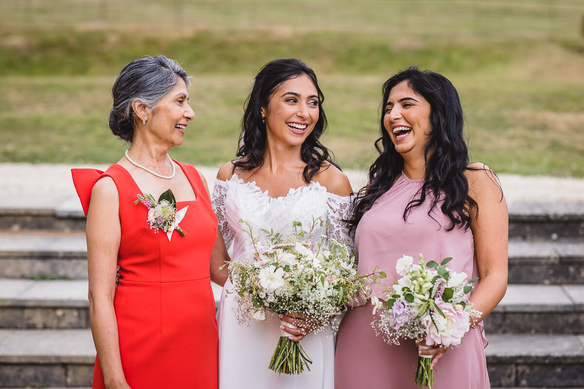 Bride laughing with her mum and sister in the grounds of Crowcombe Court