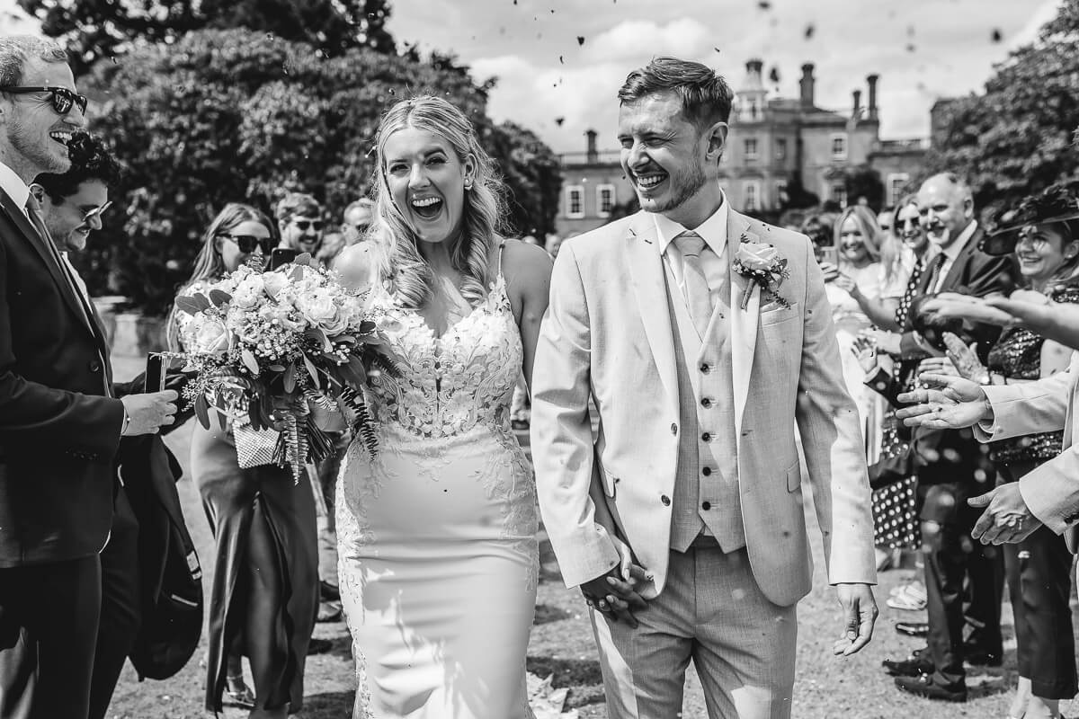 Bride and Groom smiling as they come down the confetti tunnel at Pylewell Park, Hampshire
