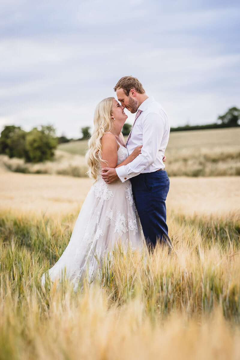 Bride and Groom cuddling in the fields at Wellington Barn in Wiltshire